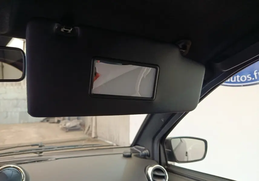 Vue intérieure du pare-soleil côté conducteur de l'Aixam Ambition 0.5 City Coupe GTI noir avec rétroviseur extérieur visible.