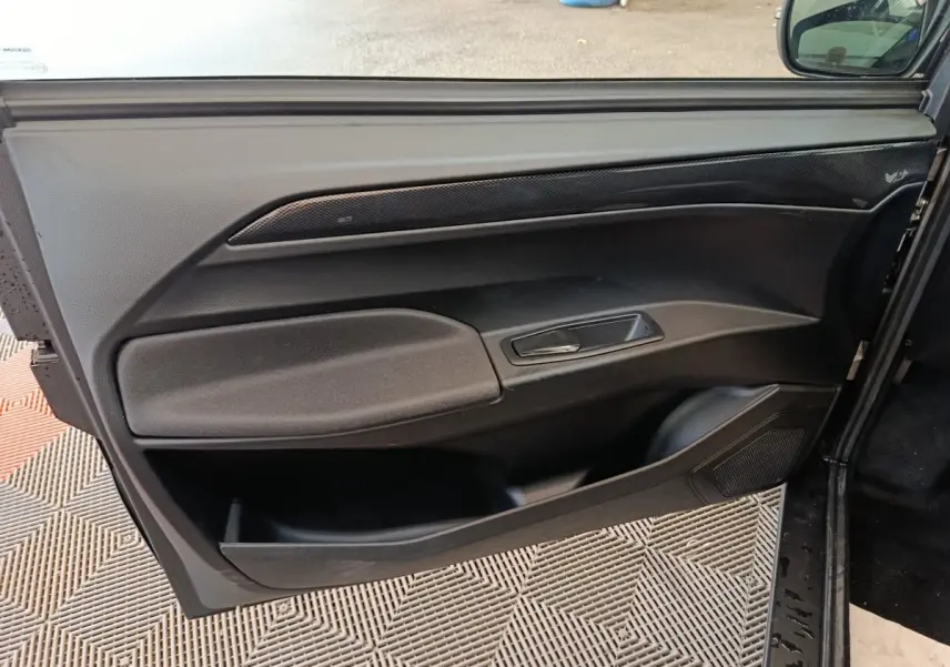 Vue intérieure de la porte côté conducteur de l'AIXAM Ambition 0.5 City Coupe GTI noire, avec poignée et rangements intégrés.