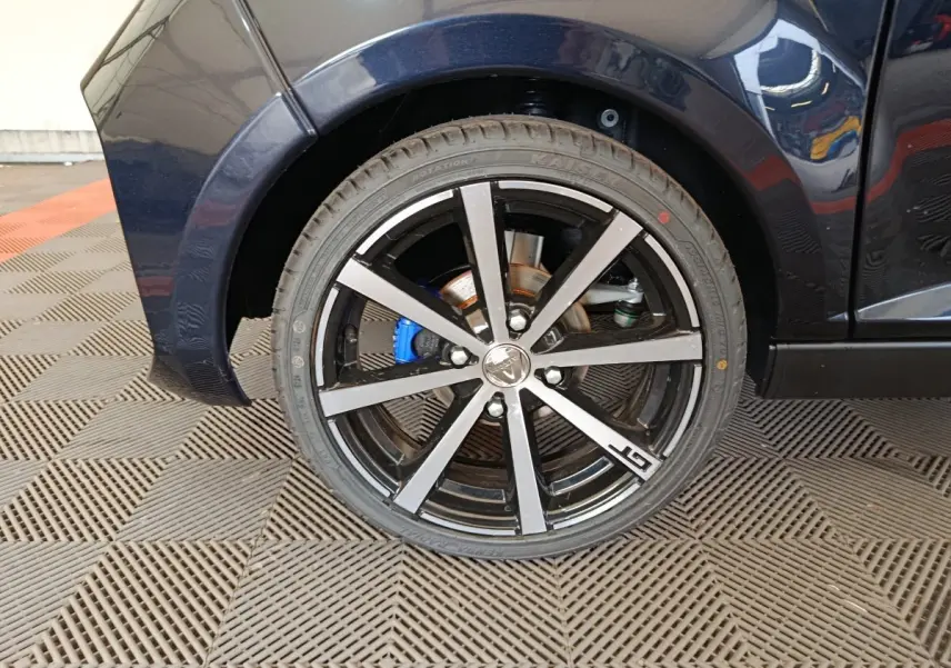 Gros plan sur la roue arrière droite noire de l'AIXAM AMBITION 0.5 CITY COUPE GTI avec jante alu bicolore et logo GTI.