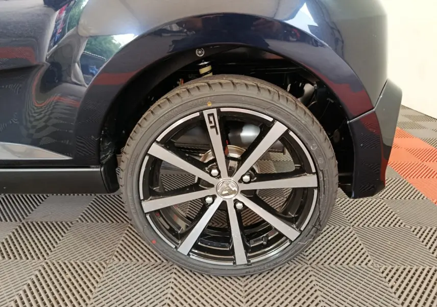 Gros plan sur la roue arrière droite noire de l'AIXAM AMBITION 0.5 CITY COUPE GTI 2026 avec jante noire et argent.