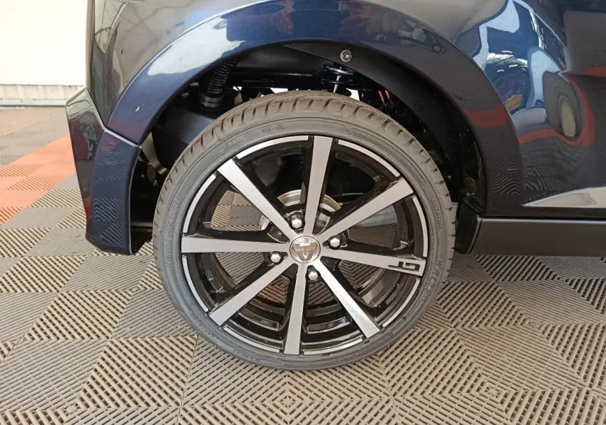 Gros plan sur la roue arrière droite noire d'une Aixam Ambition 0.5 City Coupe GTI avec jante GT en aluminium.