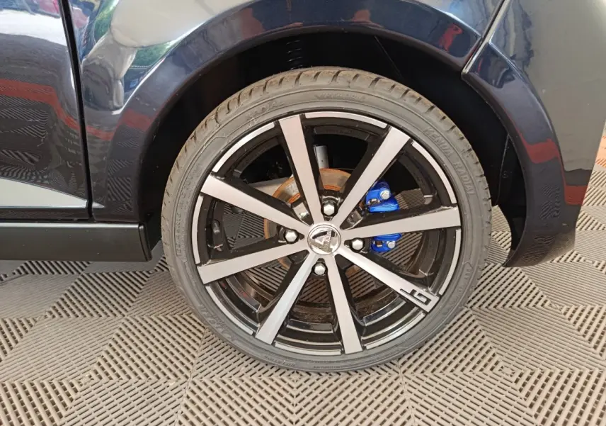 Gros plan sur la roue avant droite noire d'une Aixam Ambition 0.5 City Coupe GTI avec étrier de frein bleu.