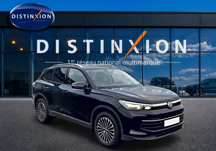 Volkswagen Tiguan 2025 noir en 3/4 avant droit, avec jantes spécifiques et phares LED allumés devant un showroom Distinxion.