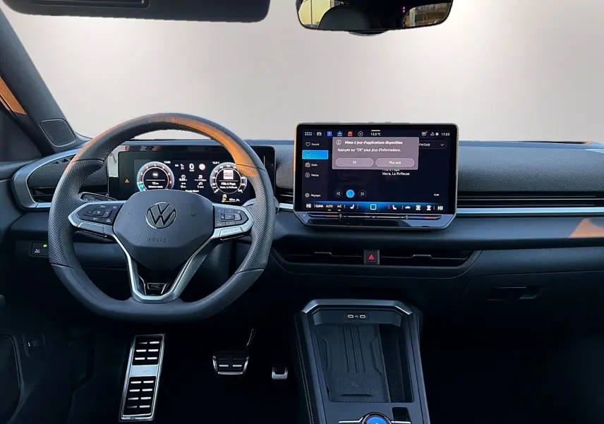 Vue intérieure frontale du tableau de bord noir du Volkswagen T-Roc 2026 avec volant cuir multifonction et écran tactile central.