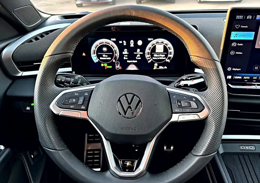 Vue rapprochée du volant sport en cuir noir perforé du Volkswagen T-Roc 2026 avec tableau de bord numérique et écran tactile.