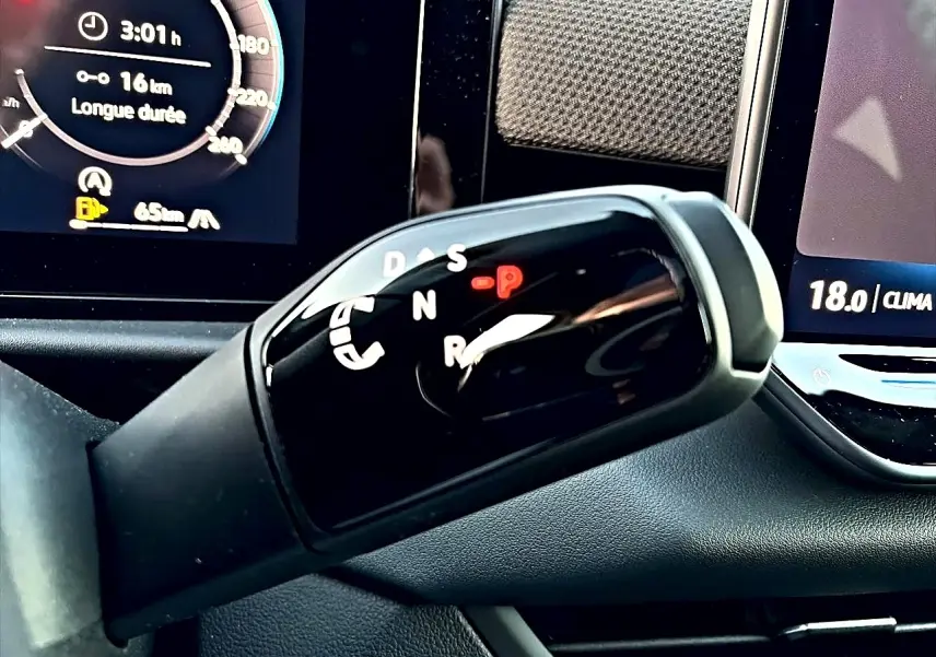 Gros plan sur le levier de vitesses automatique noir brillant du Volkswagen T-Roc 1.5 etsi 150 R-Line 2026 avec affichage digital en arrière-plan.