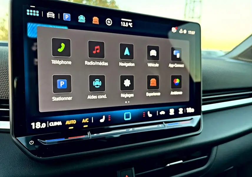 Écran tactile central du Volkswagen T-Roc 2026 affichant les menus de navigation et médias, intérieur noir.