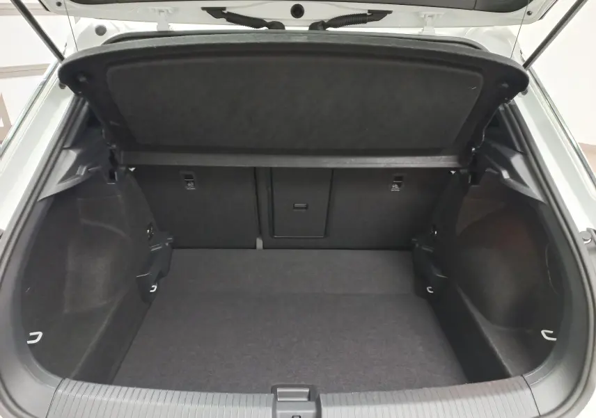 Coffre ouvert du Volkswagen T-Roc blanc pur 2025, vue intérieure montrant l’espace de chargement et la tablette arrière.