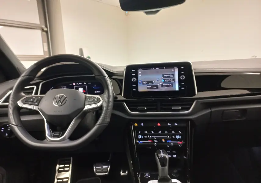 Intérieur du Volkswagen T-Roc 1.5 TSI blanc, vue du poste de conduite avec écran tactile central et volant multifonction.