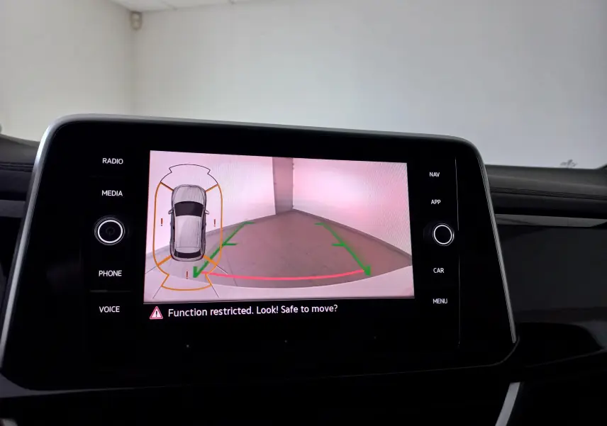 Écran central du Volkswagen T-Roc blanc affichant la caméra de recul avec guidage de trajectoire en intérieur.