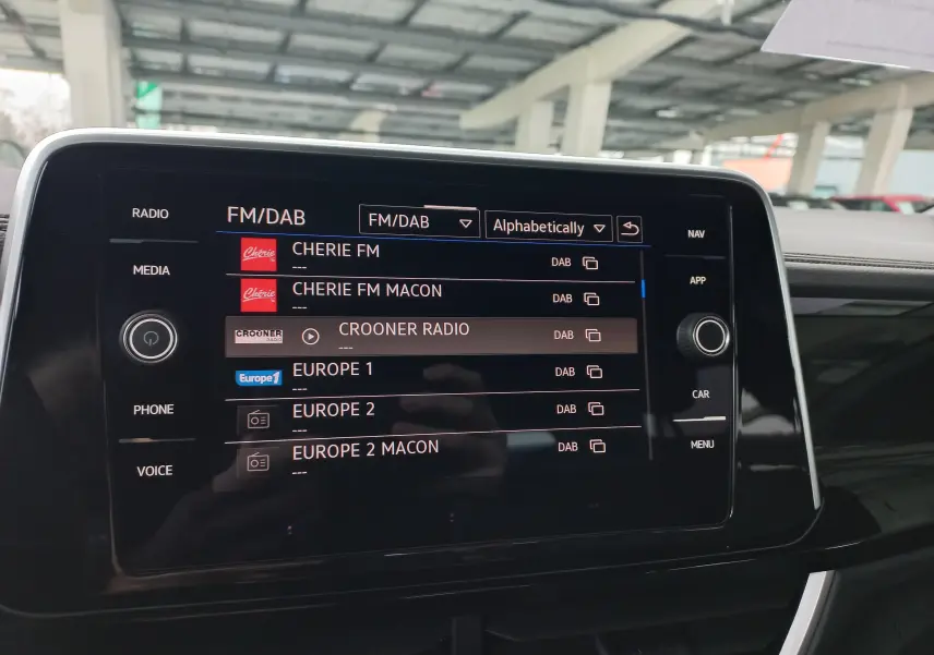 Écran tactile central du Volkswagen T-Roc 1.5 TSI R-Line Edition 2025 affichant les stations radio FM/DAB en intérieur.