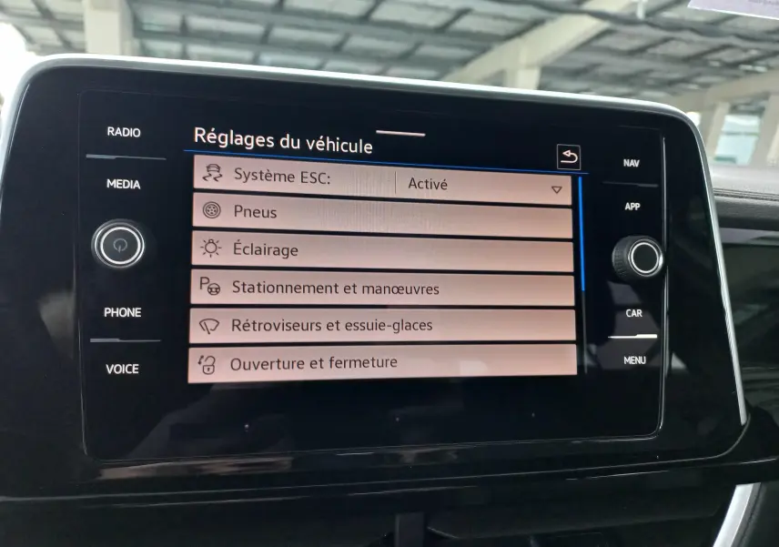 Écran tactile du tableau de bord du Volkswagen T-Roc 2025 affichant les réglages du véhicule en intérieur.
