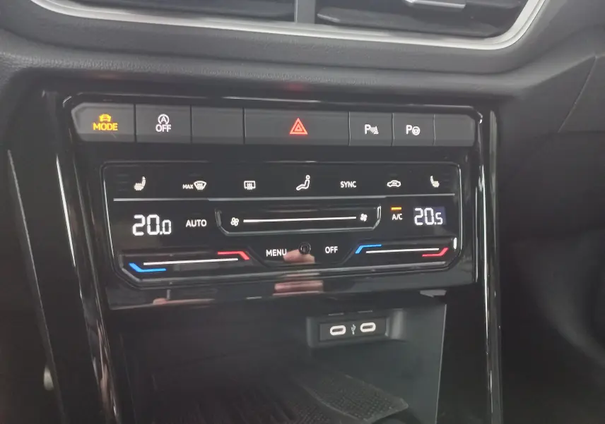 Vue rapprochée du tableau de bord du Volkswagen T-Roc 2025, montrant la commande de climatisation digitale et les ports USB.