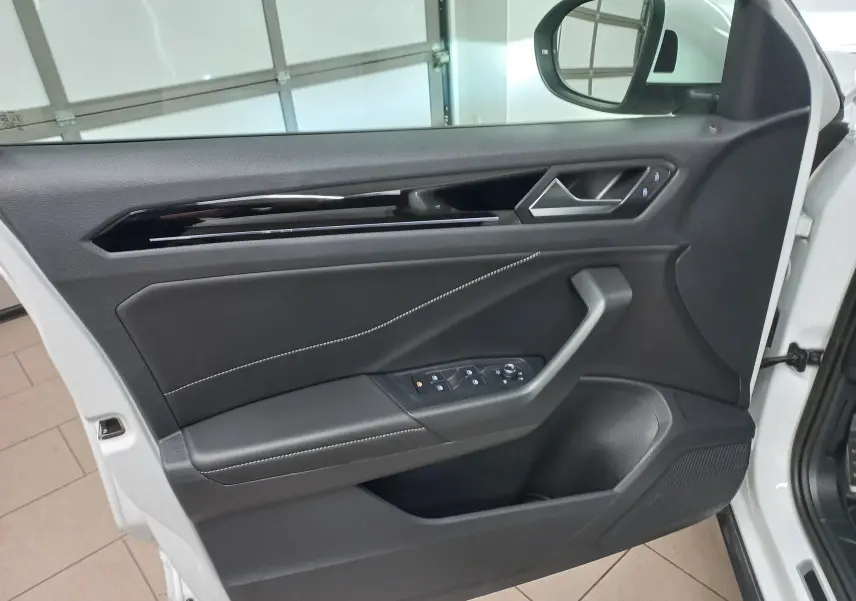 Vue intérieure de la porte avant gauche du Volkswagen T-Roc blanc pur, avec garniture noire et surpiqûres blanches.