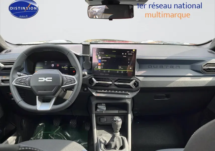 Vue intérieure avant du tableau de bord du Dacia Duster 2025 avec volant multifonction et écran tactile central.