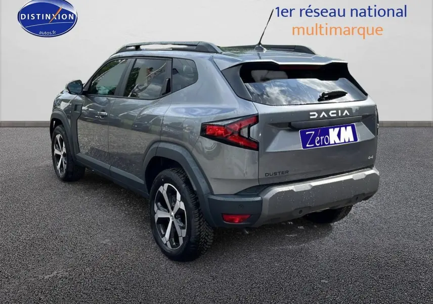Vue 3/4 arrière droite du Dacia Duster gris schiste avec barres de toit et jantes alu distinctives.