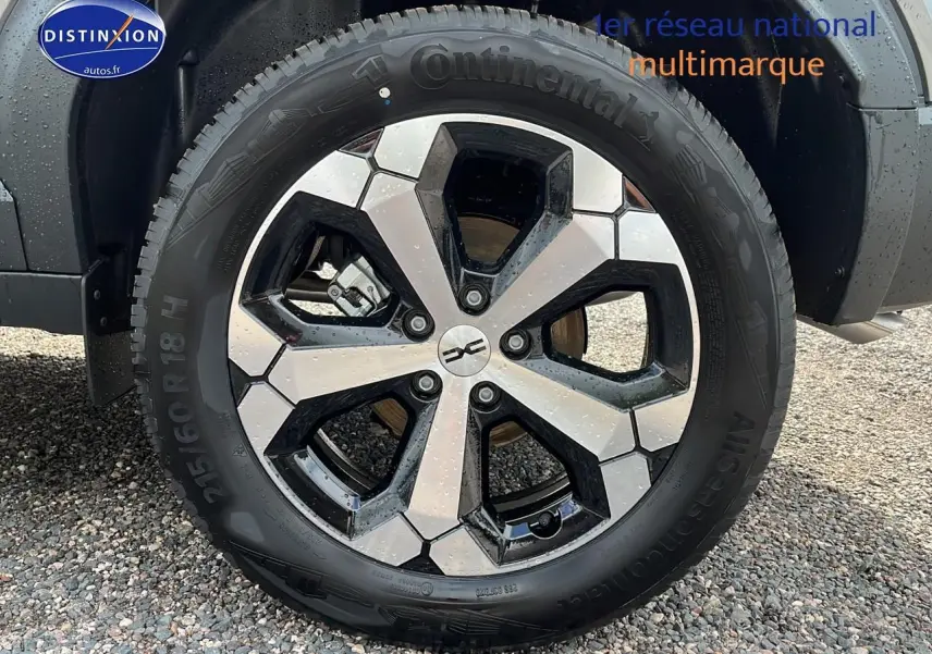 Gros plan sur la roue avant droite du Dacia Duster gris schiste, jante alu bicolore et pneu Continental.
