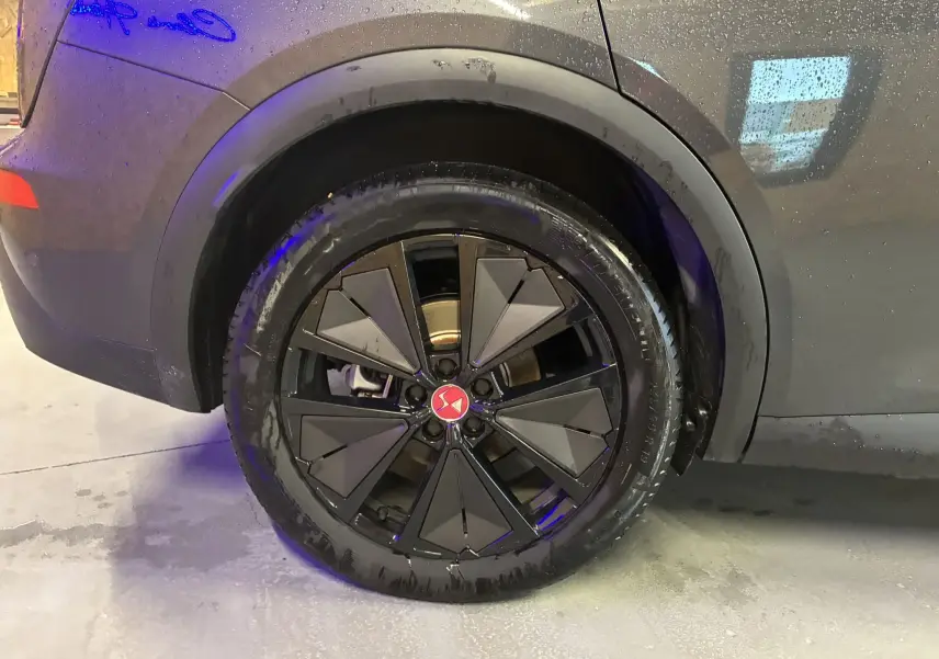 Gros plan sur la roue arrière droite du DS7 E-TENSE gris 2024 avec jante noire au design géométrique distinctif.