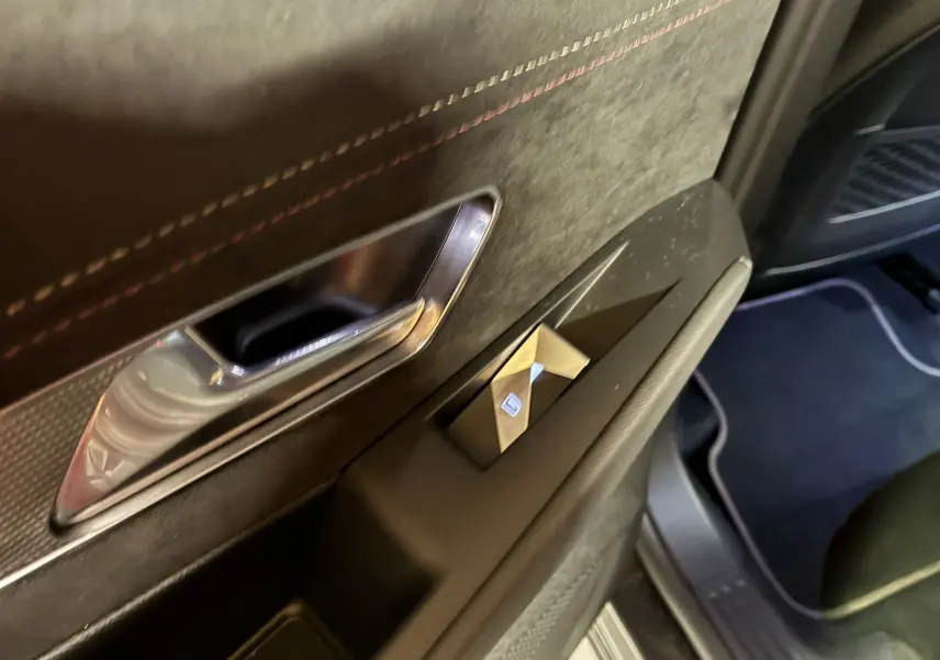 Détail de la porte intérieure côté gauche du DS7 E-TENSE 2024 gris, avec poignée chrome et bouton de lève-vitre.