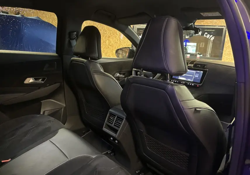 Vue intérieure arrière du DS7 E-TENSE 2024 avec sièges en cuir noir et écran tactile visible au tableau de bord.