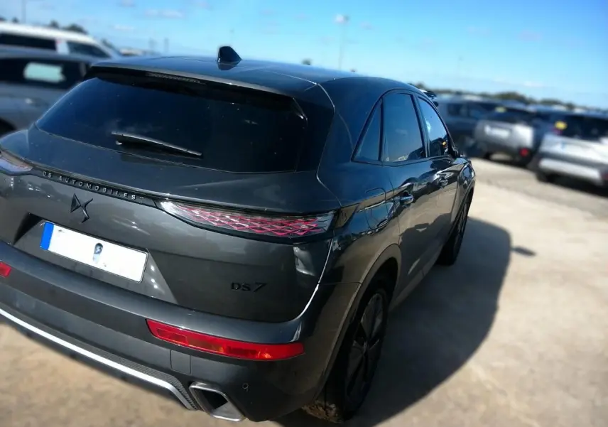 Vue 3/4 arrière droite d'un DS7 gris 2024 avec feux arrière LED et double sortie d'échappement visible.