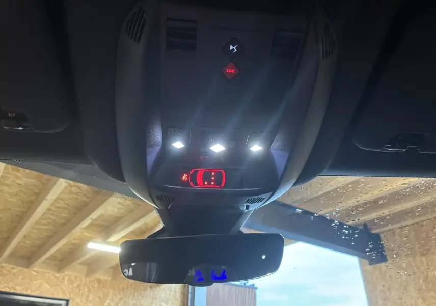 Vue intérieure du plafonnier avec commandes éclairées et rétroviseur dans un DS7 gris 2024 E-TENSE.