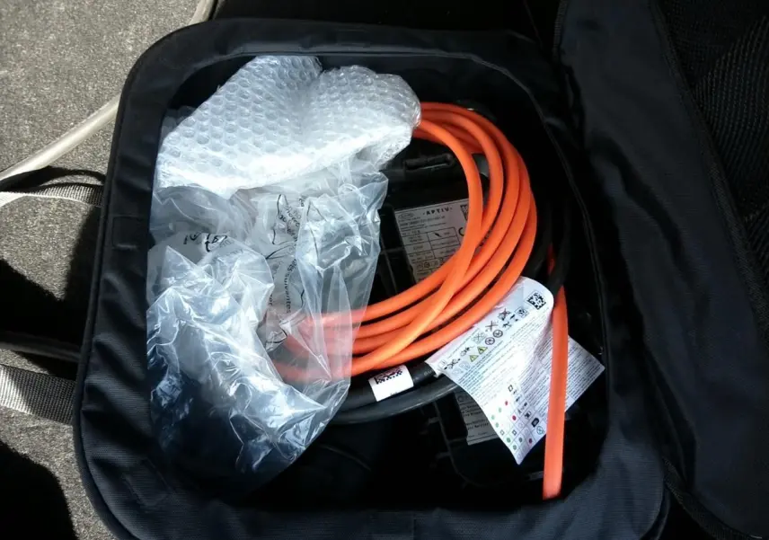 Vue rapprochée d’un câble de recharge orange dans un sac noir, accessoire du DS7 E-TENSE gris 2024.