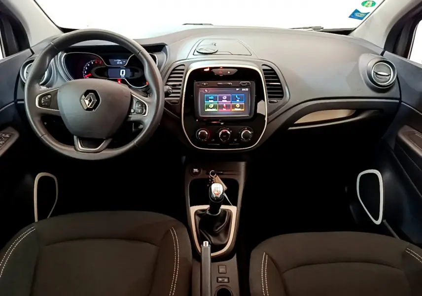Vue intérieure frontale du tableau de bord gris foncé du Renault Captur avec volant cuir multifonctions et écran tactile central.
