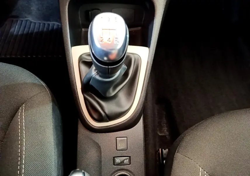 Gros plan sur le levier de vitesses manuel gris et noir du Renault Captur Business, entouré des sièges avant en tissu foncé.