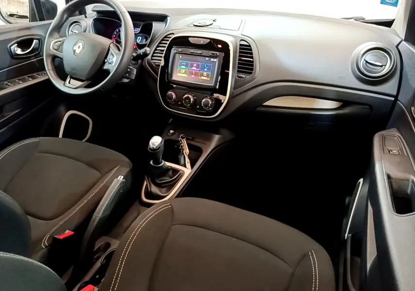 Vue intérieure côté conducteur du Renault Captur gris foncé, avec volant cuir multifonctions et écran tactile central.