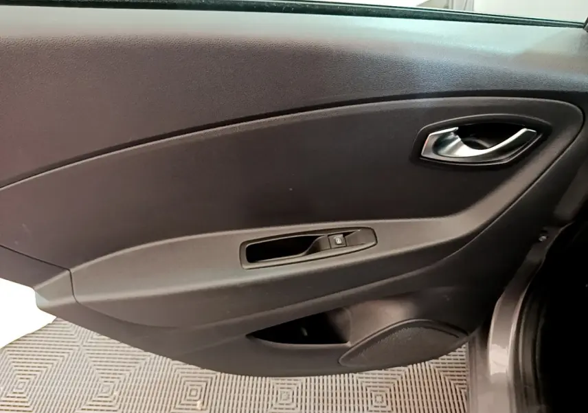 Vue rapprochée de la porte intérieure côté droit du Renault Captur gris foncé, avec poignée et commande de vitre électrique.
