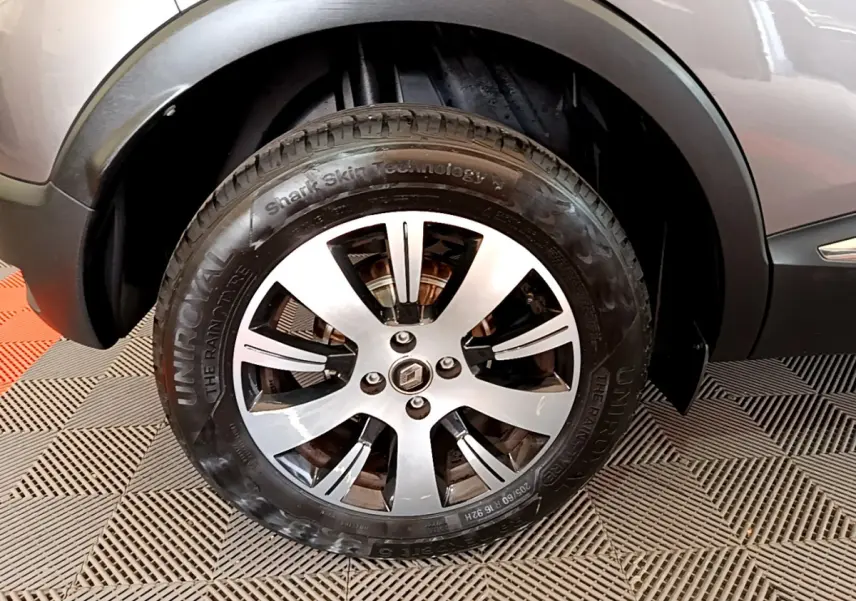 Gros plan sur la roue avant gauche du Renault Captur gris foncé, mettant en valeur la jante alliage et le logo central.