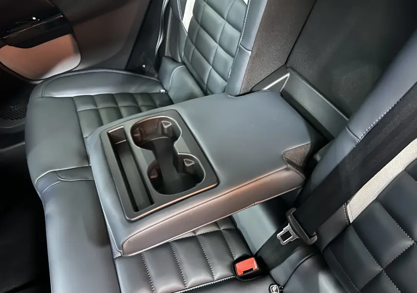 Vue rapprochée de l'accoudoir central arrière avec porte-gobelets sur les sièges en cuir gris du Citroën C5 Aircross II Hybrid.