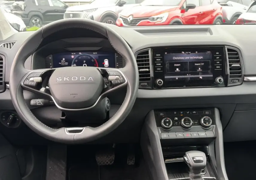 Vue intérieure centrée sur le volant SKODA noir et l'écran tactile du tableau de bord du Karoq 2025.