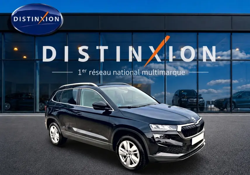 SUV Škoda Karoq noir vu en 3/4 avant droit devant une vitrine avec logo Distinxion.