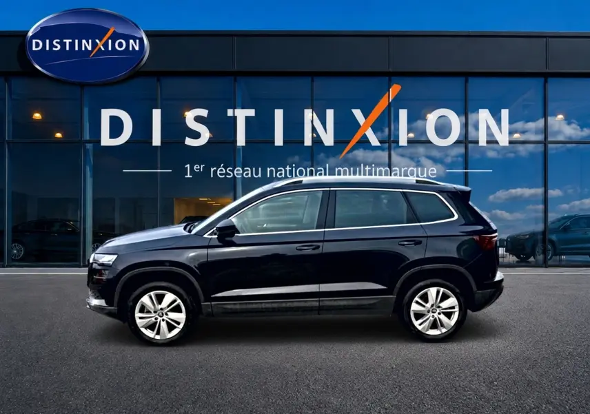 Profil côté gauche d'un Skoda Karoq noir 2025 garé devant une vitrine avec logo Distinxion.