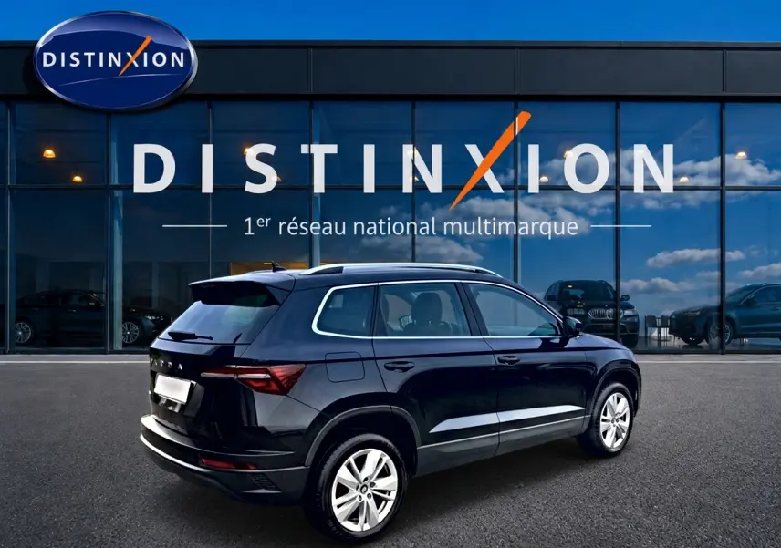 Vue 3/4 arrière droite d'un Skoda Karoq noir 2025 avec jantes alu devant une vitrine Distinxion.