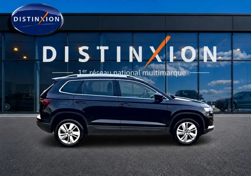 Vue latérale droite d'un Skoda Karoq noir 2025 garé devant une vitrine avec logo Distinxion.