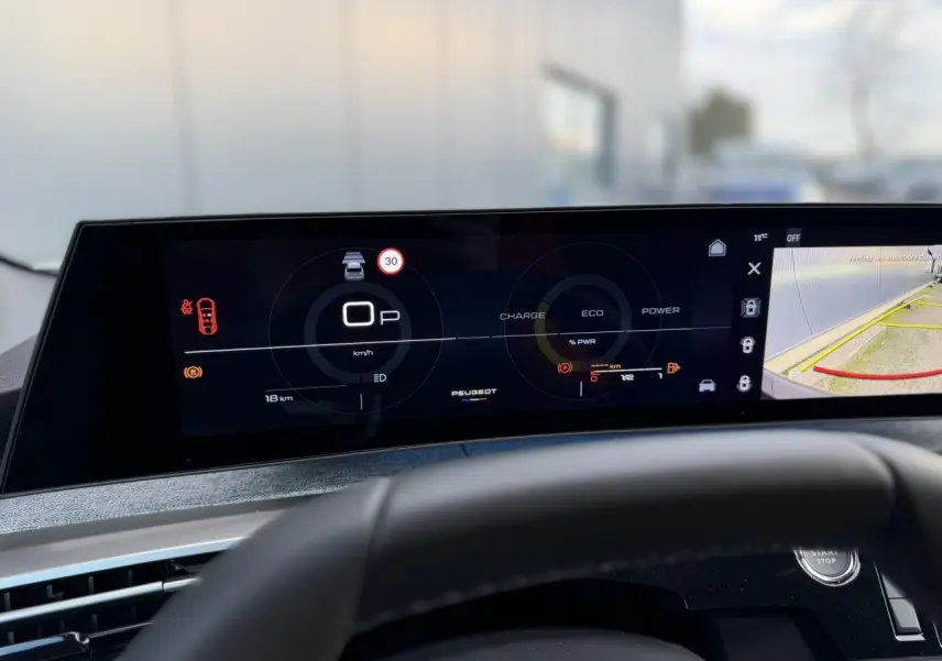 Vue rapprochée du tableau de bord numérique panoramique 21 pouces du Peugeot 3008 Hybrid blanc, affichant la caméra de recul.