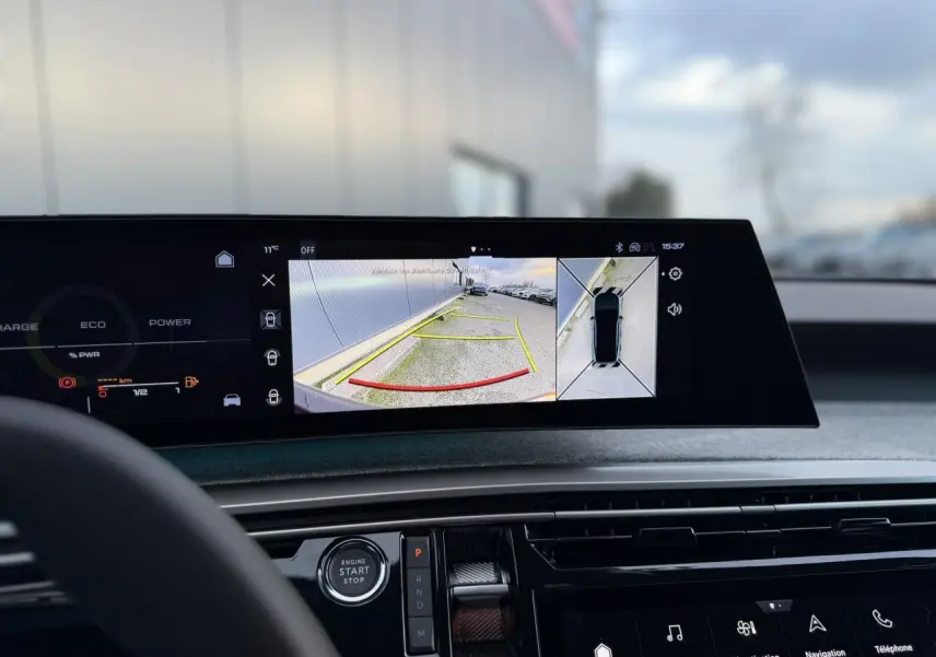 Vue intérieure du tableau de bord du Peugeot 3008 Hybrid blanc, écran panoramique affichant caméra 360° et vue arrière.