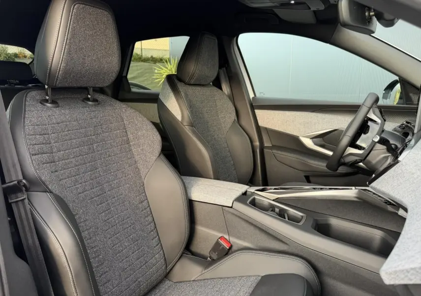 Vue intérieure côté droit du Peugeot 3008 Hybrid 145 Allure 2025, sièges tissu gris et cuir noir avec console centrale moderne.