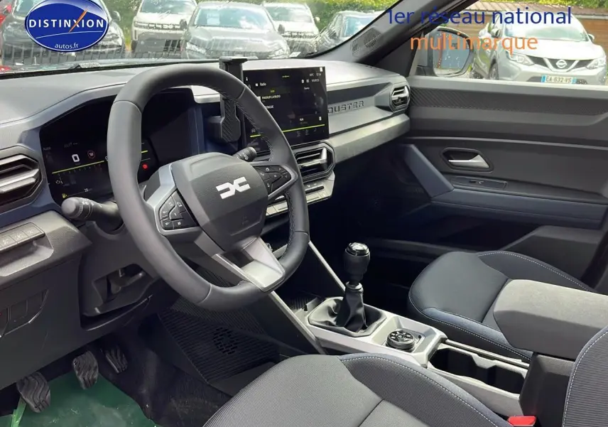 Vue intérieure côté conducteur du Dacia Duster 2025 gris schiste, volant multifonction et écran tactile central visibles.