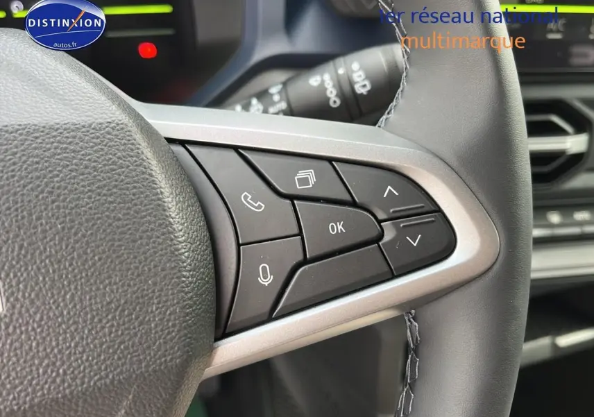 Gros plan sur les commandes multifonctions du volant du Dacia Duster 2025, intérieur noir avec détails argentés.