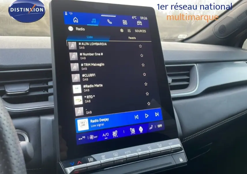 Vue intérieure centrée sur l'écran tactile vertical du tableau de bord du Renault Symbioz gris Cassiopée, affichant la radio.