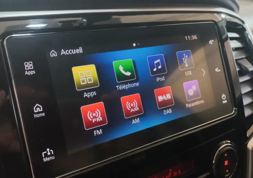 Écran tactile central du tableau de bord du Mitsubishi L200 gris foncé, affichant le menu multimédia.