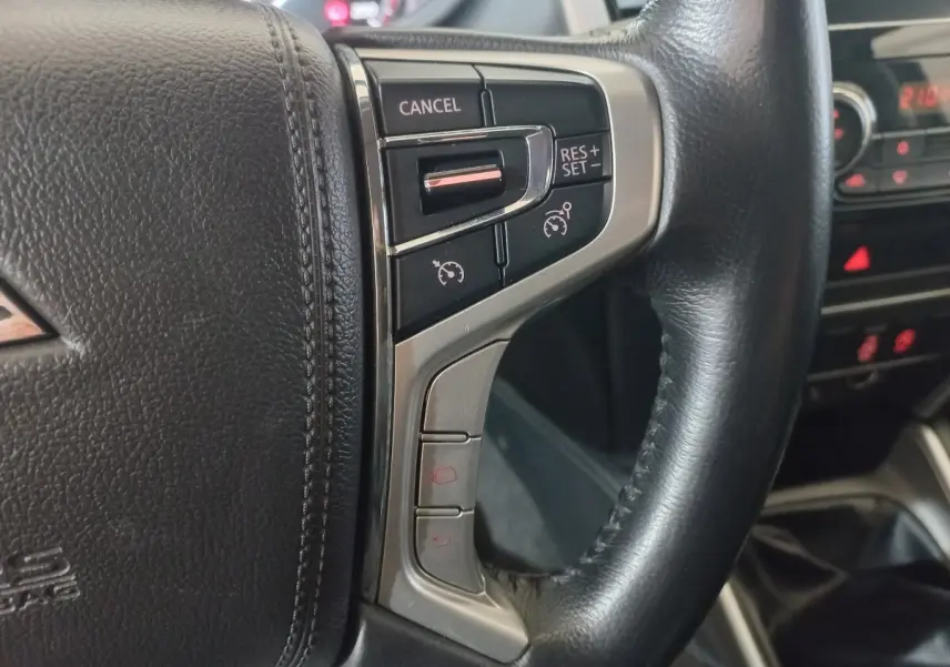 Gros plan sur le volant cuir noir du Mitsubishi L200 2020, avec commandes de régulateur de vitesse intégrées.