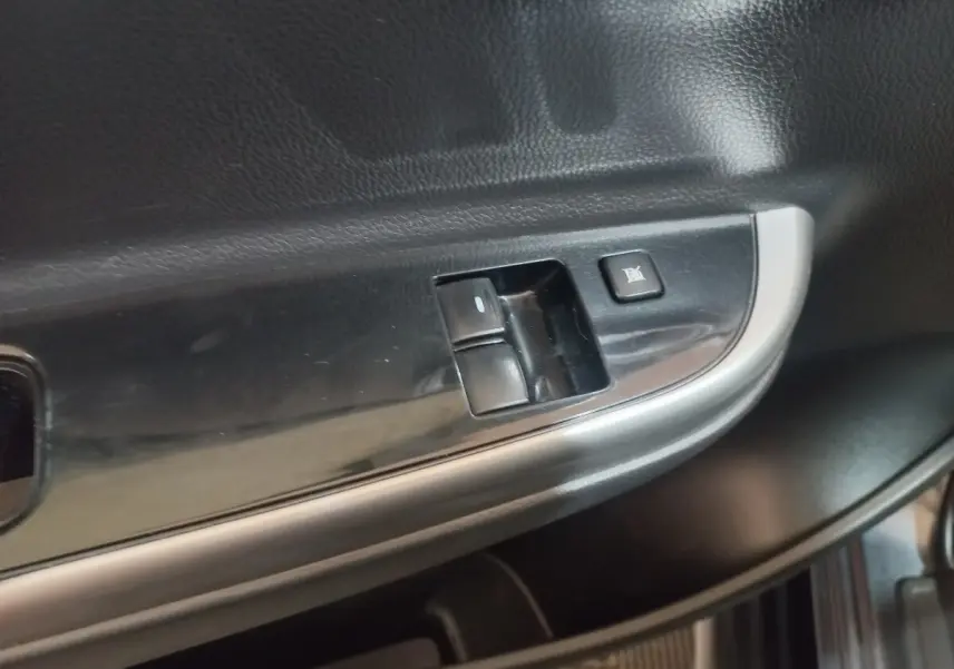 Gros plan sur les commandes de lève-vitre et verrouillage sur la porte intérieure côté conducteur du Mitsubishi L200 gris foncé.