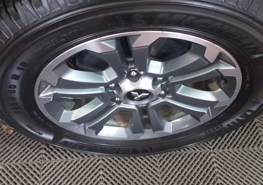 Gros plan sur la jante aluminium gris foncé d’un Mitsubishi L200 avec pneu Michelin Cross 255/60 R18.