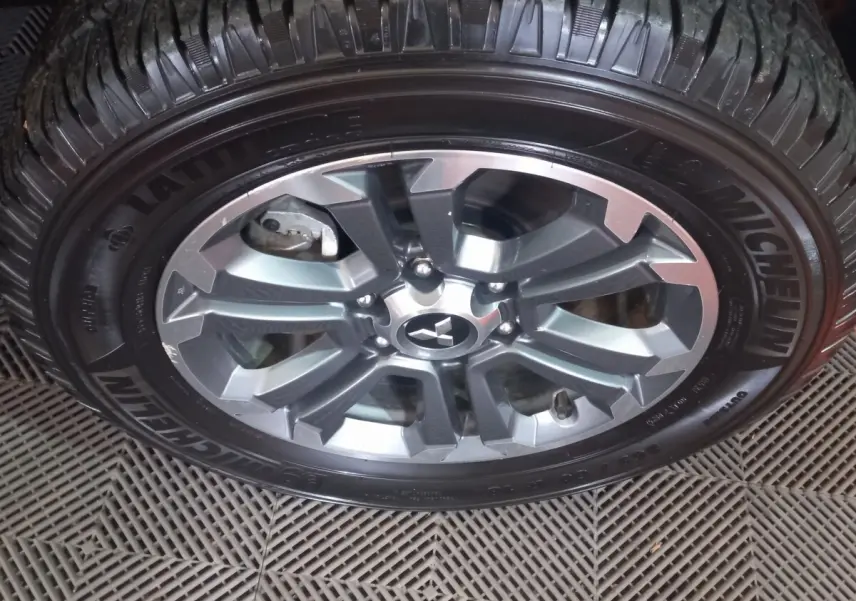 Gros plan sur la roue en alliage gris du Mitsubishi L200 avec pneu Michelin visible sur un sol texturé.