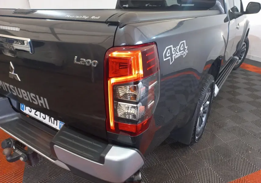 Vue 3/4 arrière droite du pick-up Mitsubishi L200 gris foncé avec feux arrière allumés et logo 4x4 Diff Lock visible.
